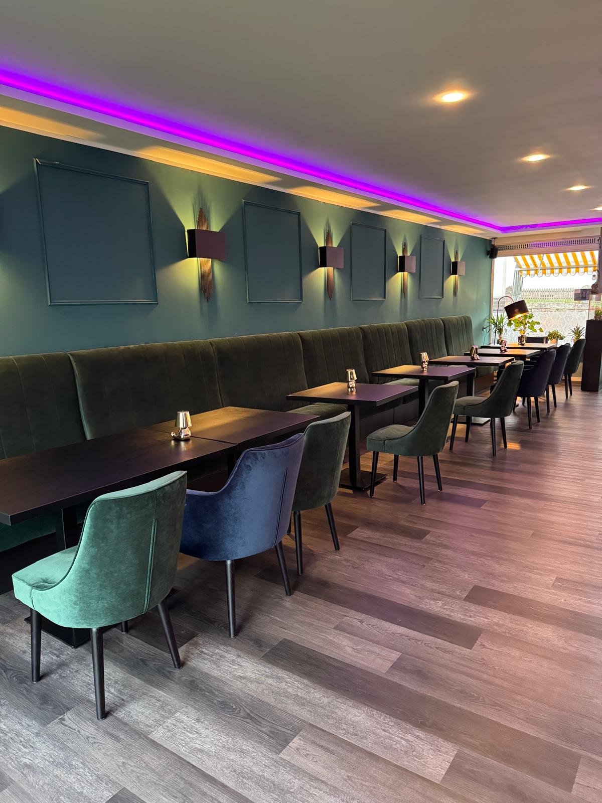 Innenraum mit Samtstühlen, langer Sitzbank und violetter LED-Beleuchtung